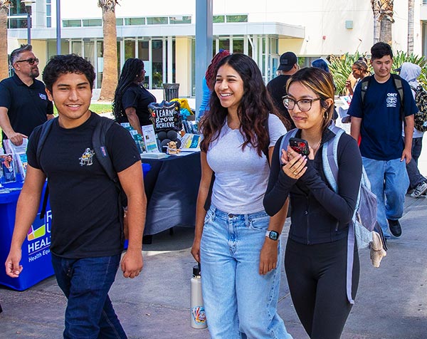 A group of smiling students walks across Coudures Plaza