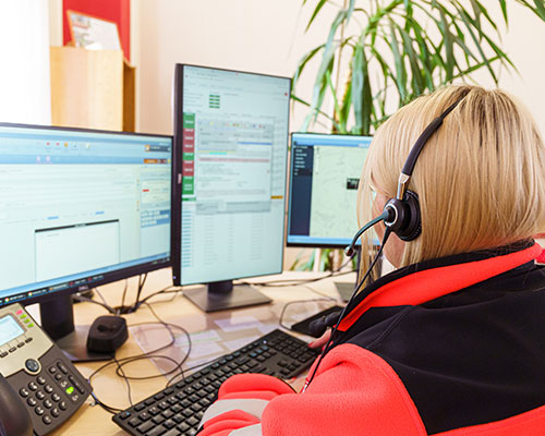 A dispatch worker sits at a 3-monitor computer