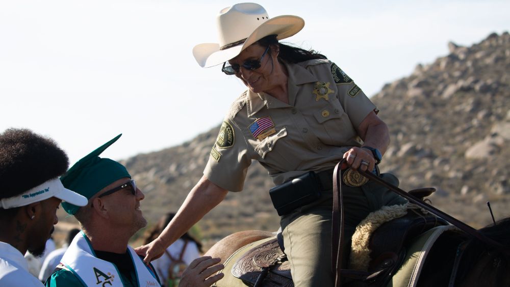 Laurie Crouse, a posse member, congratulates gradutes