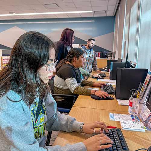 Students work on computers with the help of educational advisors