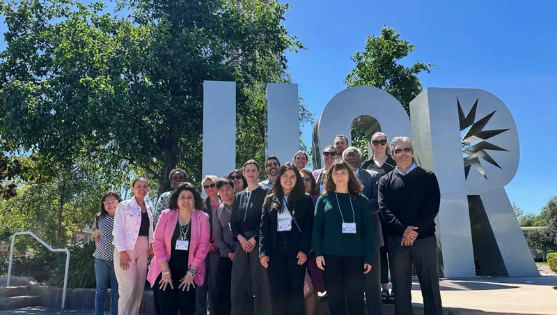 HTCC attendees stand in front of the UCR monogram sculpture