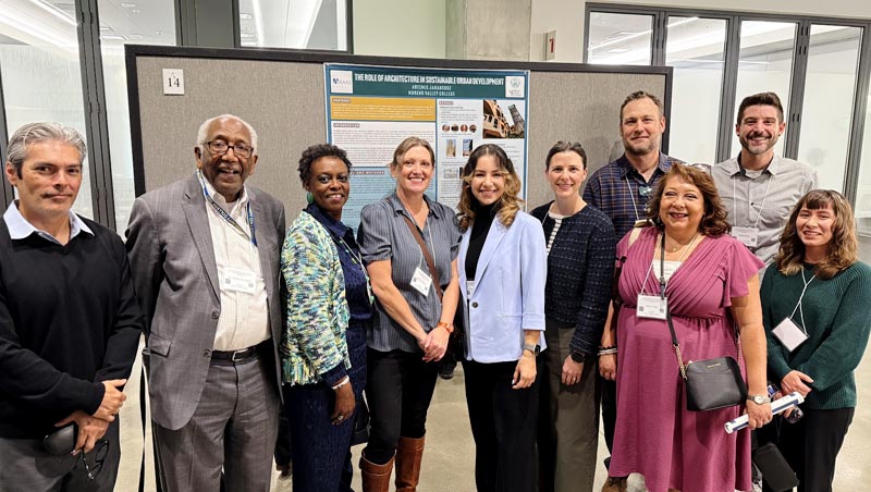 Honors students, faculty, and College leaders stand together in front of presented research posters