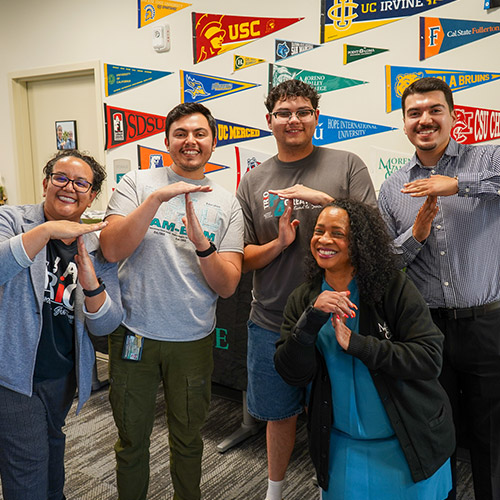 A group of students and staff making a T for TRIO with their hands